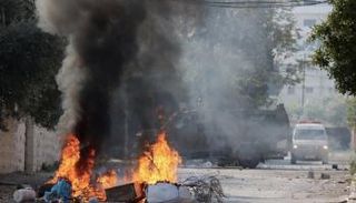 سيارة إسعاف تمر قرب آلية للجيش الإسرائيلي في جنين