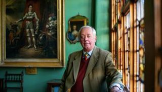 فرانسيس ديموك وخلفه صورة مرسومة لدور الفارس الذي تلعبه عائلته 