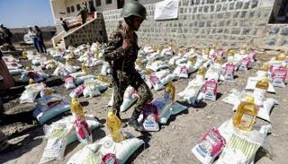 مسلح حوثي يتفقد مساعدات إنسانية مقدمة لليمنيين