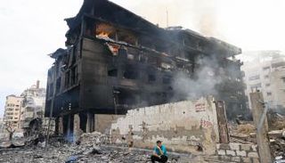 فلسطيني أمام مبنى متفحم عقب غارات إسرائيلية على غزة