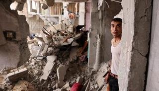 فلسطيني يقف وسط أنقاض منزل دمرته غارة إسرائيلية على غزة - أ.ف.ب