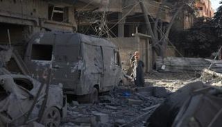 أشخاص يتفقدون الأضرار التي لحقت بمخيم النصيرات للاجئين في وسط قطاع غزة