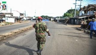 جندي من الشرطة العسكرية السيرالونية يحيي رجلاً على طول طريق شاغر في فريتاون