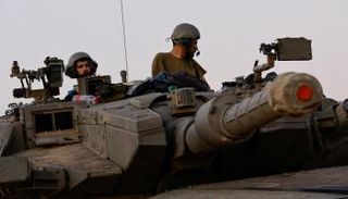 جنديان إسرائيليان فوق دبابة قرب غزة - رويترز