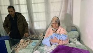 والدة الطفل ريان تحمل رضيعها