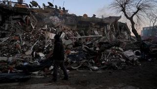 رجل يقف أمام مبنى منهار في قهرمان مرعش