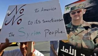 مواطن سوري يرقع لافتة ترفض العقوبات الأمريكية على سوريا - أرشيفية