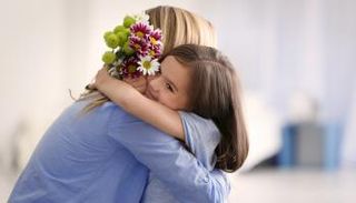 فتاة تحتضن أمها وتقدم لها وردا في عيدها - أرشيفية