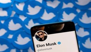 حساب إيلون ماسك على Twitter على هاتف ذكي موضوع على شعارات تويتر - رويترز