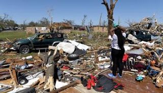 امرأة تقف في منطقة دمّرها الإعصار