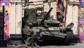 عنصر من فاغنر يمشي أمام دبابة بمدينة روستوف- رويترز