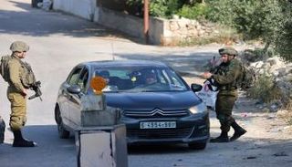 جنود إسرائيليون يقفون على حاجز على مدخل قرية عوريف الفلسطينية، جنوب مدينة نابلس