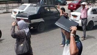 مارة يحتمون من أشعة الشمس