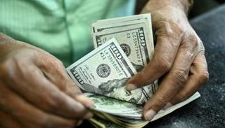 أحد عملاء البنوك يقوم بعد كميات من الدولار - أرشيفية