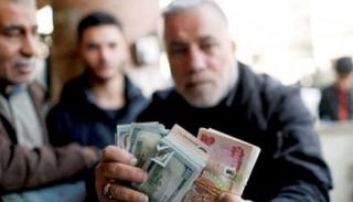 مواطن يعرض عملات ورقية للدينار والدولار - أرشيفية