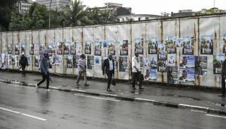 مارة يسيرون قرب لافتات انتخابية في أبيدجان