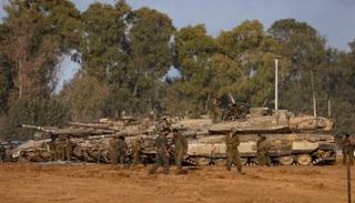 جنود إسرائيليون يقفون بجانب دبابات بعد عودتهم من العملية البرية المستمرة بغزة