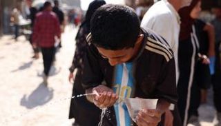 طفل فلسطيني يشرب من كيس صغير في خان يونس