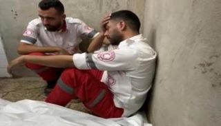 المسعف يجلس إلى جانب جثمان والدته
