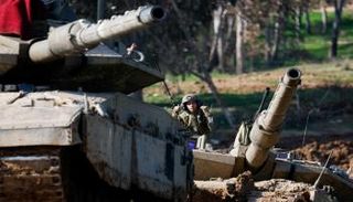 جندي إسرائيلي يشير إلى أعلى دبابة بالقرب من حدود غزة