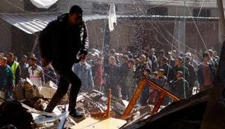 فلسطينيون في غزة يتابعون عمليات رفع انقاض منزل قصفته إسرائيل