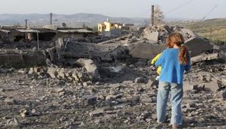 فتاة تتفقد الأضرار التي لحقت بمبنى بعد يوم من غارة إسرائيلية على قرية بلبنان