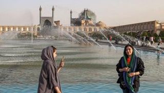 زوار يلتقطون الصور بجوار النافورة في ساحة نقش جهان التاريخية