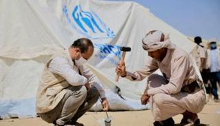 عامل في منظمة أممية يساعد في نصب خيمة للنازحين باليمن - أرشيفية