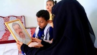 السيدة اليمنية نجلاء وأطفالها يتطلعون لصورة زوجها المختطف