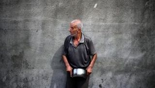 فلسطيني يحمل قدرا فارغا للحصول على وجبة طعام في ظل انتشار المجاعة بغزة