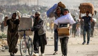 فلسطينيون يحملون أكياسًا من المساعدات الإنسانية قرب ممر نتساريم