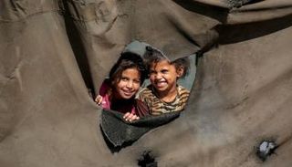 أطفال ينظرون من ثقب خيمة للنازحين شمال النصيرات