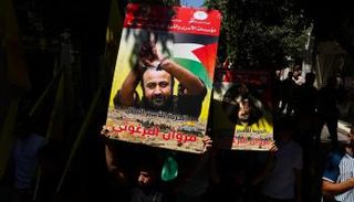 متظاهرون يرفعون لافتات عليها صور البرغوثي