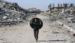 طفل فلسطيني أمام منازل مدمرة بغزة