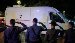 عناصر من الشرطة الإسرائيلية يلقون التحية خلال مرور سيارة تنقل جثامين رهائن