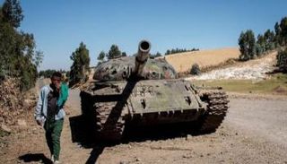 شاب إثيوبي يمر إلى جانب دبابة بإقليم تيغراي - أرشيفية
