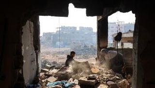 نازحة فلسطينية مع حفيدها بين الأنقاض