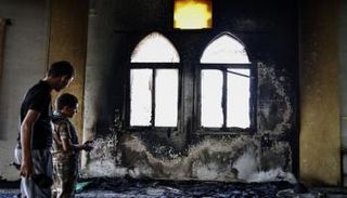 فلسطينيان يتفحصان المسجد المحترق
