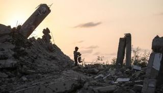 طفل فلسطيني يقف على ركام منزل عائلته في غزة