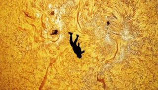 مصور يوثق صورة لمظلي يبدو وكأنه يسقط أمام سطح الشمس