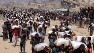 فلسطينيون في غزة يحملون أجولة المساعدات - أرشيفية