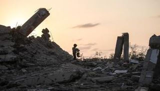 طفل فلسطيني يفتش في أنقاض المباني المهدمة بغزة