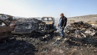 فلسطيني يتفقد سيارات عقب هجوم مستوطنين