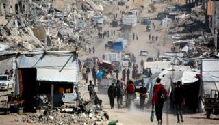 فلسطينيون يسيرون بين الركام في غزة