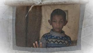 طفل ينظر من خيمة في حي الزيتون بمدينة غزة