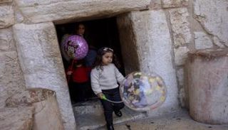 أطفال يحملون بالونات يمرون عبر باب التواضع في كنيسة المهد