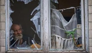 أوكراني ينظر من نافذة مبنى تعرض لهجوم بكييف