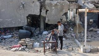 فلسطيني يجلس لقص شعره وسط الأنقاض في جباليا