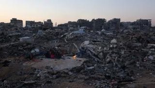 عائلة فلسطينية تجلس على أنقاض منزلها أثناء إفطارها في جباليا بغزة