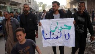 شاب فلسطيني يحمل لافتة عليها شعار مناهض لحماس في بيت لاهيا
